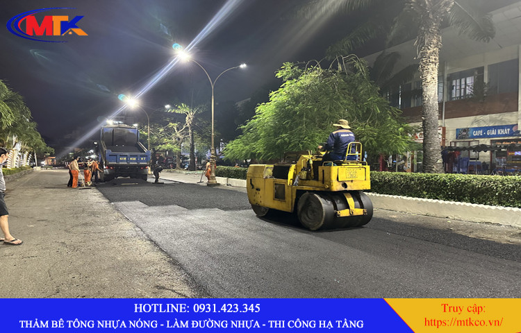 Hình ảnh cận cảnh công nhân kiểm tra chất lượng mặt đường nhựa sau khi lu lèn, đảm bảo đạt tiêu chuẩn kỹ thuật