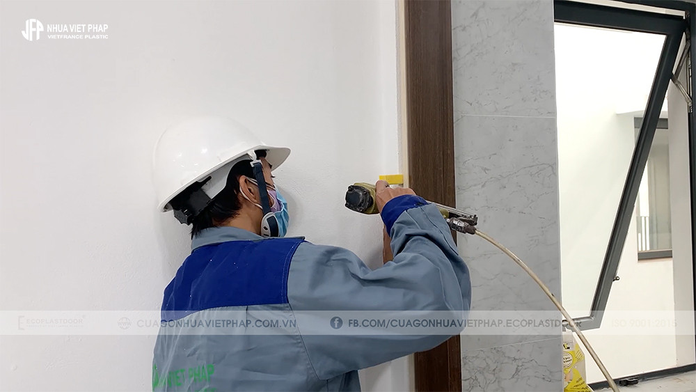 Thợ đang dựng và cố định khung bao cửa nhựa composite lên ô chờ tường