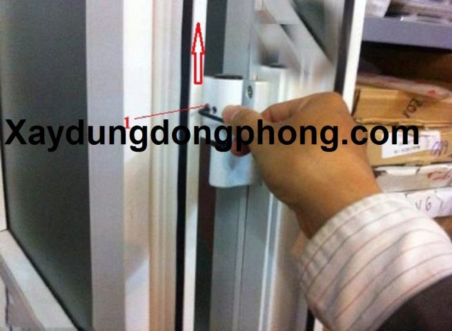 Dụng cụ tua vít lục giác đang điều chỉnh ốc vít trên bản lề cửa nhựa để khắc phục tình trạng cửa bị xệ.